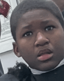 a young boy is getting his hair cut at a barber shop and looking at the camera .