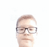 a young boy wearing glasses looks at the camera in front of a blue sky
