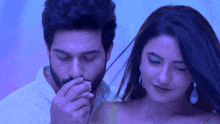a man and a woman are standing next to each other . the man is touching the woman 's nose .