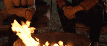 a man and a woman are sitting around a campfire