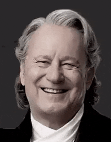 a man with gray hair is smiling and wearing a tuxedo .
