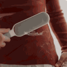 a woman is using a brush to remove hair from her sweater .