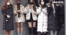 a group of women wearing face masks are standing next to each other in front of a building that says cbc news on it