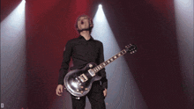 a man playing a guitar on a stage with the letter d in the corner