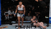 a woman in a ufc top and shorts is standing in a cage