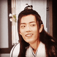 a young man with long hair is smiling and making a face