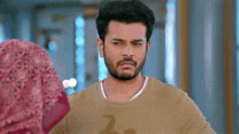a man with a beard is standing next to a woman wearing a hijab and making a funny face .