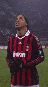 a soccer player wearing a red and black jersey with the ac milan logo