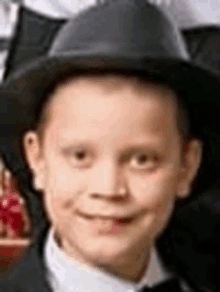 a young boy wearing a black hat and a bow tie is smiling for the camera .