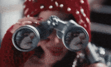 a woman is looking through binoculars with a cat on the lenses