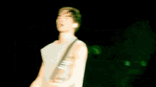 a man is playing a guitar on a stage with a green background .