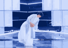 a man in a white dress stands on a stage with chinese writing on the bottom