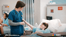 a nurse is talking to a patient in a hospital room with the number 112 on the wall