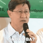 a man with glasses is holding a microphone and says ano pa ba