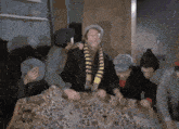 a group of men are gathered around a table with a leopard print rug and one of them is wearing a yellow and black scarf
