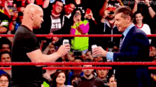 two men in a wrestling ring are toasting each other with beer .