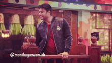 a man in a black jacket is standing on a railing with the name monikagoswamirk written below him