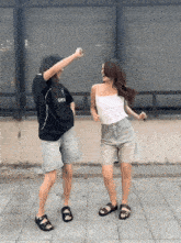 two women are dancing in front of a fence with one wearing a black shirt that says gmtn