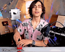 a man in a pink shirt is opening a coca cola can in front of a microphone