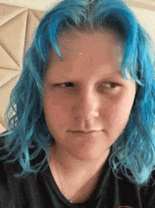 a girl with blue hair is wearing a black shirt and making a face