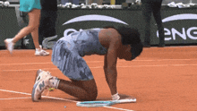 a woman is kneeling down on a tennis court with a sign that says eng in the background