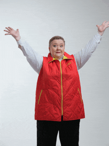 a woman wearing a red vest with a yellow zipper has her arms up