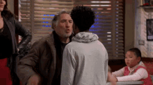 a man with a beard is talking to another man in a restaurant while a little girl sits at a table .