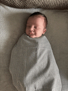 a baby is wrapped in a striped blanket and smiling
