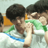 a man in a green and white shirt is being hugged by other people