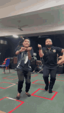a group of men are dancing in a room with a ceiling fan .