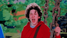 a young boy in a red hoodie is screaming while holding onto a chain
