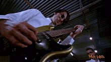 a man playing a guitar in front of a man laksa ad