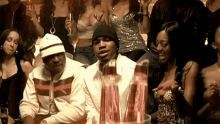 a man in a white jacket is sitting in front of a crowd of women
