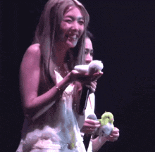 a woman holding a microphone and a stuffed animal