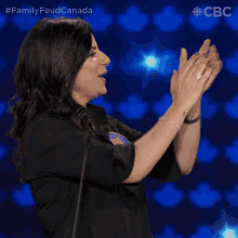 a woman applauds in front of a blue background with the letters cbc visible