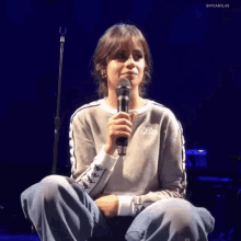a woman in a kappa sweatshirt holds a microphone in her hand