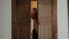 a woman is standing in a doorway with the door open .