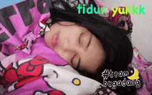 a woman is sleeping in a bed with a hello kitty blanket on it
