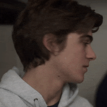 a close up of a young man 's face wearing a hoodie