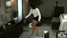 a woman in a white shirt and black shorts is dancing in a room