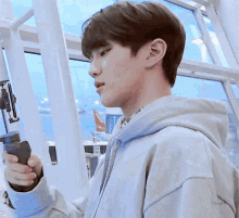a man in a hoodie is holding a remote control in his hand