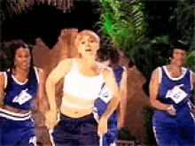 a group of women in blue and white jerseys are dancing together