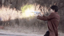a man in a brown coat is holding a gun that is shooting a beam of light .