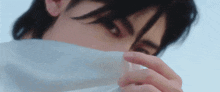 a close up of a person covering their face with a piece of paper .