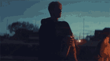 a man in a hoodie is standing in the dark holding a frisbee .