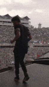 a man in a black shirt is walking on a stage in front of a crowd
