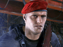 a man wearing a red beret holds a knife in his hand
