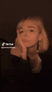 a woman in a white tank top is making a tik tok video