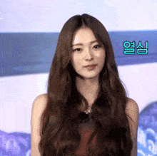 a woman with long brown hair is standing in front of a blue background with chinese characters