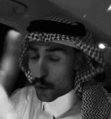a black and white photo of a man wearing a keffiyeh and a white shirt .